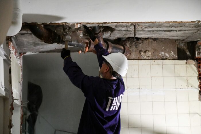 Trabajador reparando tuberías en construcción.